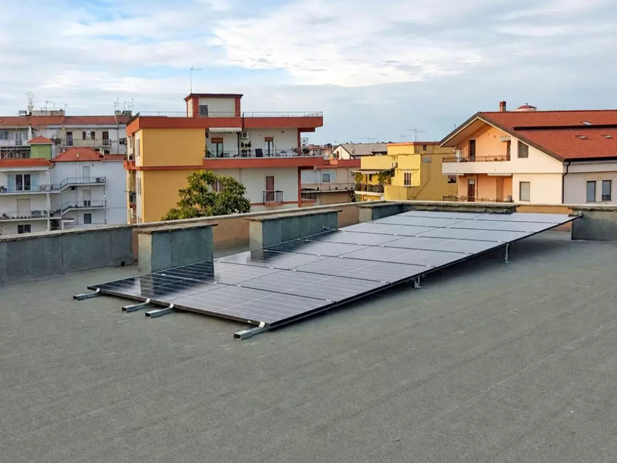 Pannelli fotovoltaici installati a regola d'arte sul lastrico solare di un condominio a Policoro con vista sulle case circostanti.