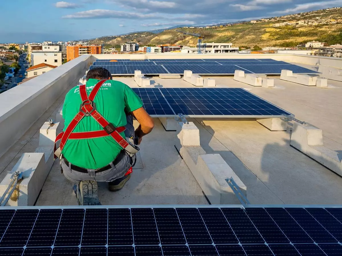 Tecnico Enersave specializzato durante il montaggio dei moduli solari su zavorre in cemento per un tetto condominiale a Cosenza.