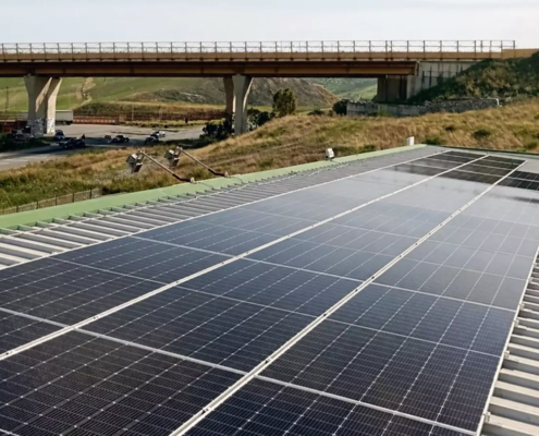 Distesa di moduli fotovoltaici per l'autoconsumo di un'impresa a Catanzaro, nei pressi di un viadotto stradale.