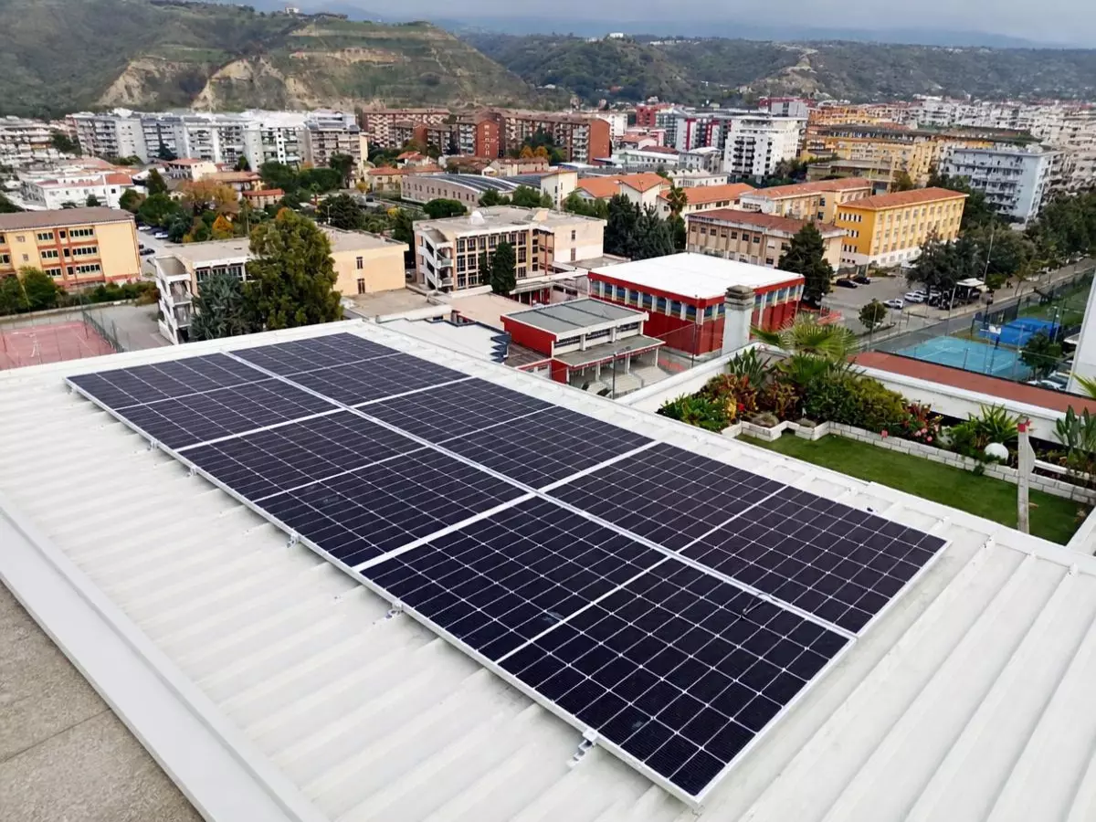 Inquadratura dall'alto dei moduli di un impianto fotovoltaico da 8 kW sul tetto di un appartamento a Cosenza vicino a un terrazzo con piante